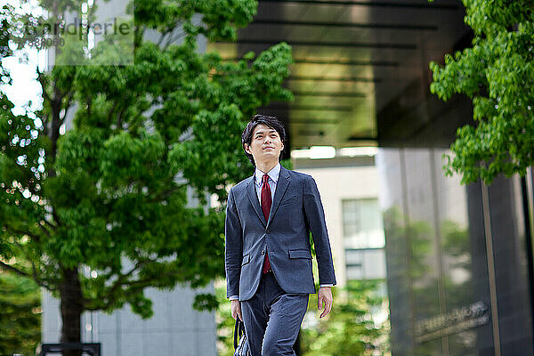 Japanischer Geschäftsmann geht im Geschäftsviertel spazieren