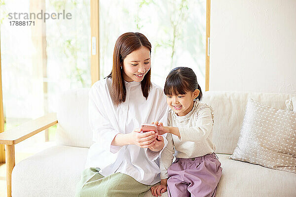 Japanisches Kind und Mutter nutzen Smartphone zu Hause