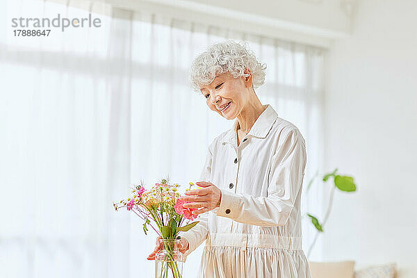 Japanische Seniorin beim Blumenbinden zu Hause