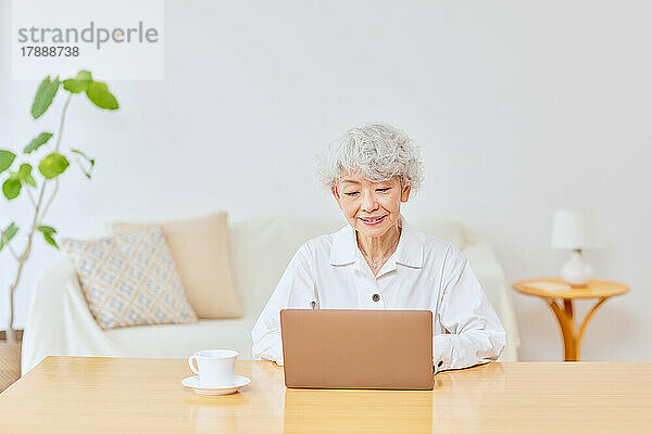 Japanische Seniorin benutzt Laptop zu Hause
