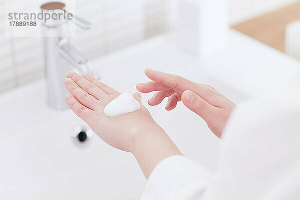 Japanerin wäscht sich die Hände mit schäumender Handseife