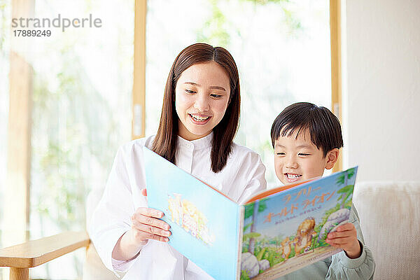 Japanisches Kind und Mutter lesen zu Hause ein Buch