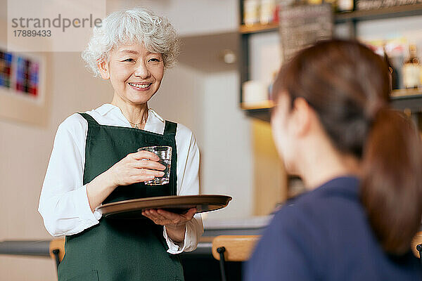 Japanische ältere Frau  die in einem Restaurant arbeitet