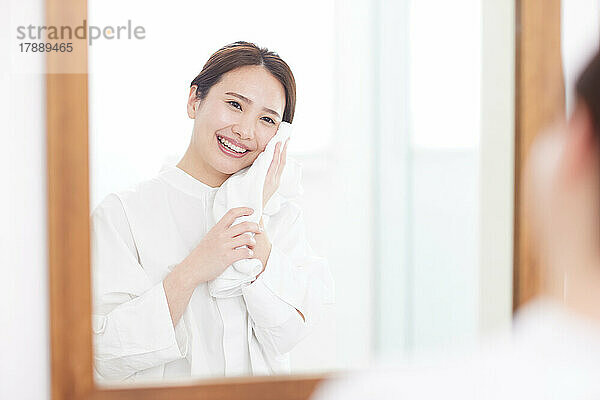 Japanische Frau wäscht zu Hause Gesicht