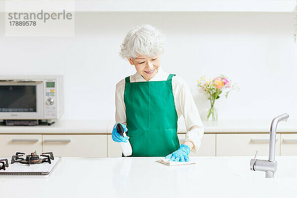 Japanische Seniorin beim Putzen der Küche