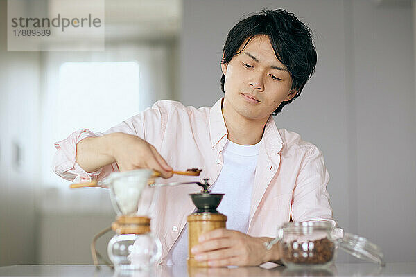 Japaner  der zu Hause Kaffee mahlt