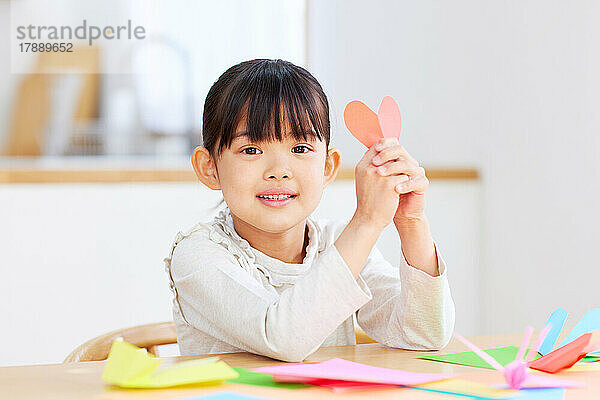 Japanisches Kind spielt zu Hause mit Origami