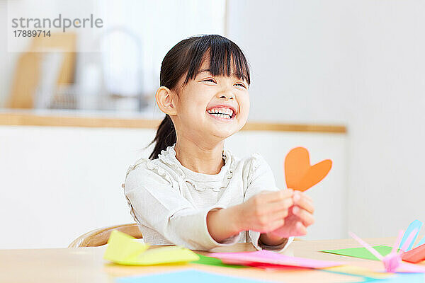 Japanisches Kind  das zu Hause mit Origami spielt