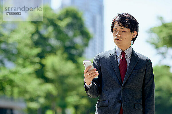 Japanischer Geschäftsmann nutzt Smartphone