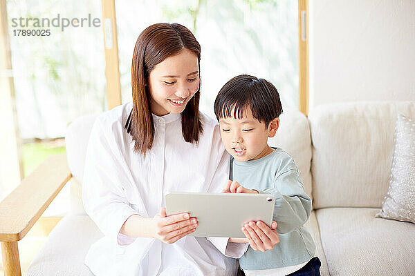 Japanisches Kind und Mutter nutzen Tablet zu Hause