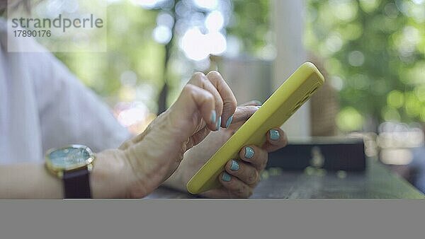 Nahaufnahme der Hände einer reifen Frau  die ein Smartphone benutzt. Weichzeichner
