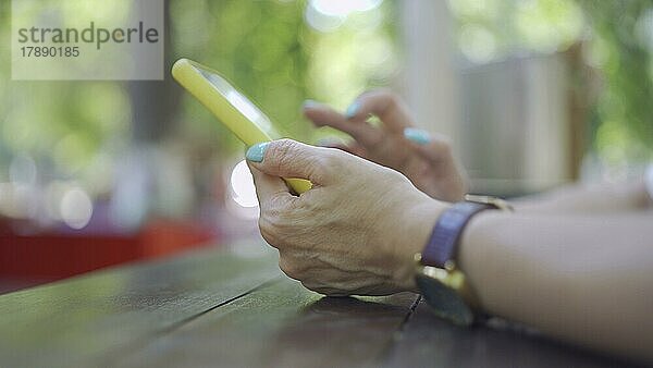 Nahaufnahme der Hände einer reifen Frau  die ein Smartphone benutzt. Weichzeichner