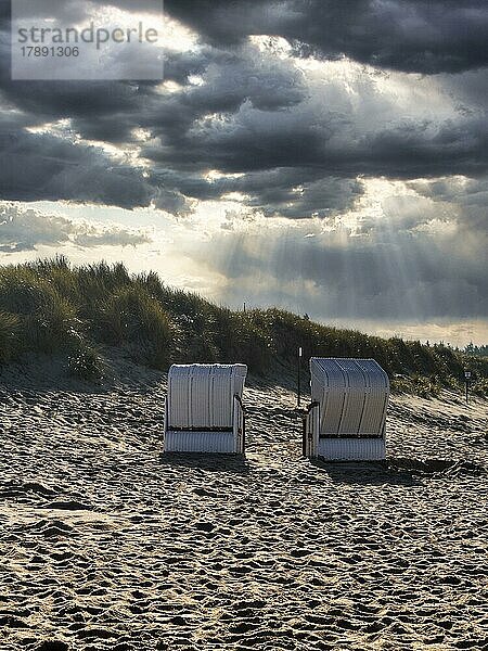 Zwei Strandkörbe vor Düne im Herbst  Sonnenstrahlen durch Wolkendecke  Gegenlicht  Utersum  Insel Föhr  Nordfriesland  Nordsee  Schleswig-Holstein  Deutschland  Europa