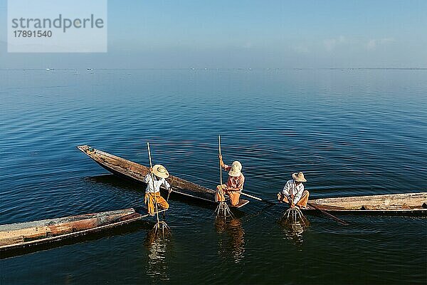 Myanmar Reiseattraktion Wahrzeichen  drei traditionelle birmanische Fischer fischen auf Booten am Inle See in Myanmar berühmt für ihre unverwechselbare einbeinige Ruderstil