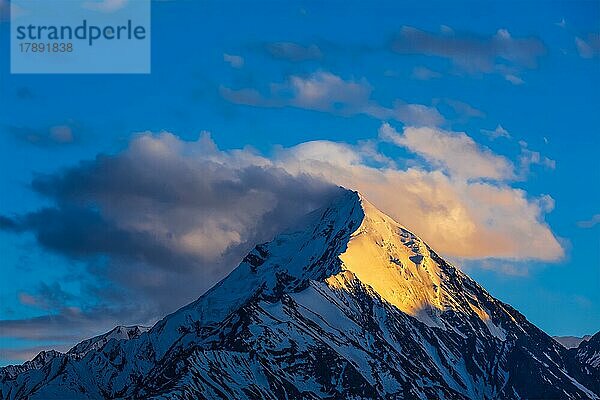 Schneebedeckter Gipfel eines Berges im Himalaya in Wolken bei Sonnenuntergang. Himachal Pradesh  Indien  Asien