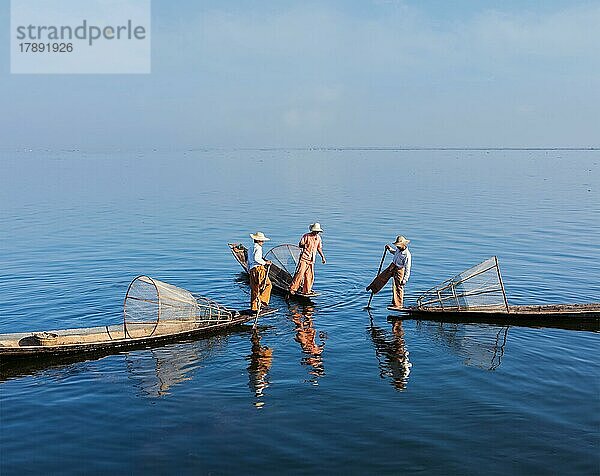 Myanmar Reiseattraktion Wahrzeichen  drei traditionelle birmanische Fischer mit Fischernetzen auf Booten am Inle-See in Myanmar berühmt für ihren unverwechselbaren einbeinigen Ruderstil