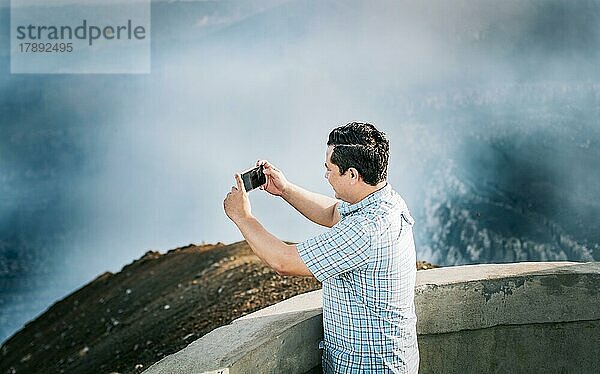 Junger Tourist beim Fotografieren auf einem Aussichtspunkt. Hombre aventurero con su celular tomando fotos en un mirador  Turista tomando fotos en un mirador