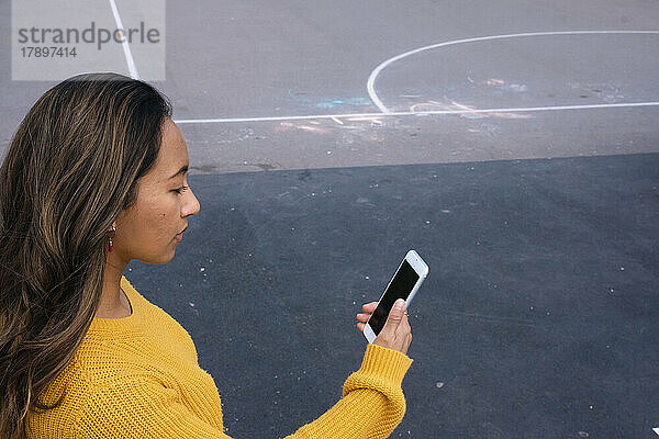 Frau bei Videoanruf mit Smartphone auf Sportplatz