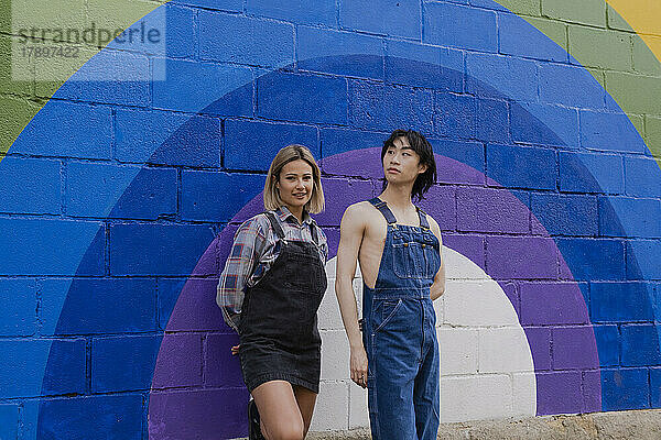 Freunde stehen neben einem an die Wand gemalten Regenbogen