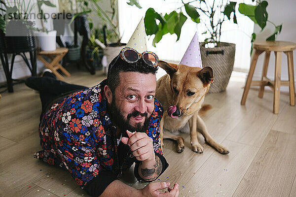 Lächelnder Mann  der zu Hause Wurst von seinem Hund isst