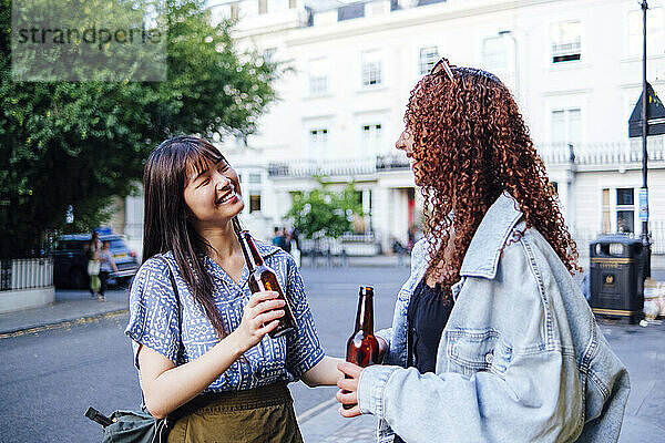 Fröhliche junge Freunde mit Bierflaschen stehen in der Stadt