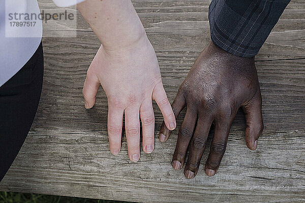 Woman touching boyfriend's finger on wooden bench