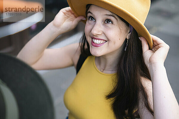 Lächelnde Frau  die am Marktstand einen Hut anprobiert