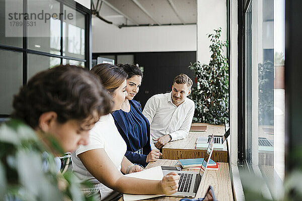 Geschäftsfrau mit Kollegen  die im modernen Büro am Laptop arbeiten