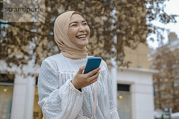 Happy young woman holding smart phone