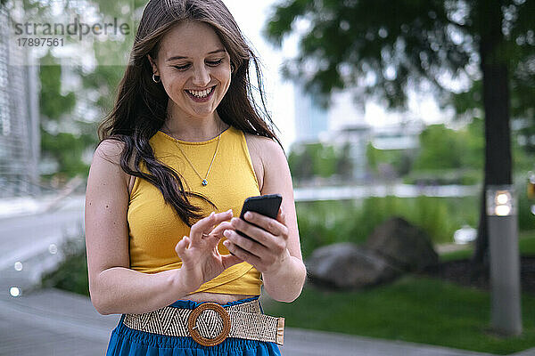 Junge Frau benutzt Smartphone im Park