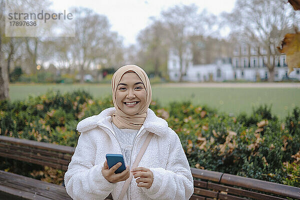 Glückliche Frau mit Smartphone im Park