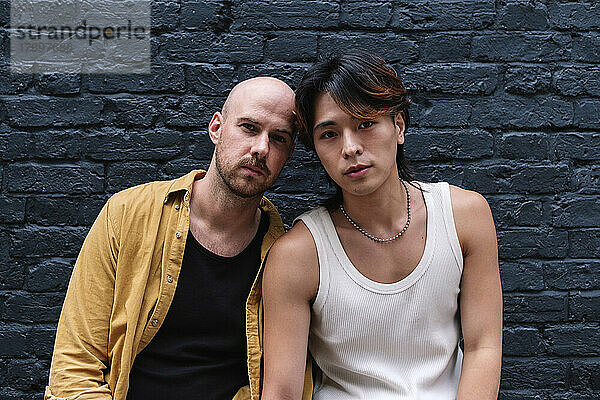 Gay couple in front of black brick wall