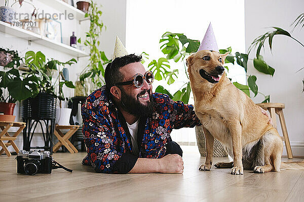 Glücklicher Mann mit Sonnenbrille  der zu Hause neben seinem Hund liegt