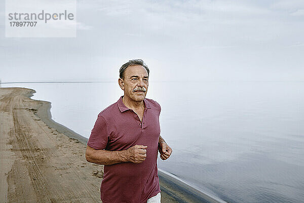 Älterer Mann läuft am Strand