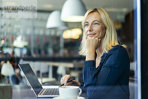 Nachdenkliche Geschäftsfrau mit Laptop sitzt im Café