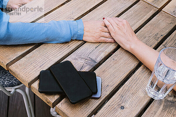 Kollege berührt einen Stapel Smartphones auf dem Tisch im Restaurant mit der Hand