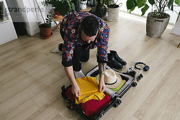 Mann packt zu Hause Kleidung in Koffer