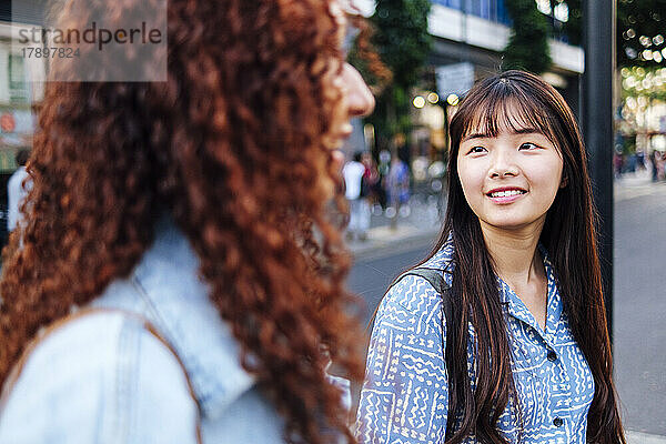 Smiling woman with friend walking on street