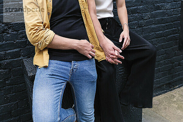 Gay couple holding hands in front of wall