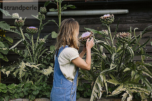 Reife Frau hält Blume vor der Pflanze