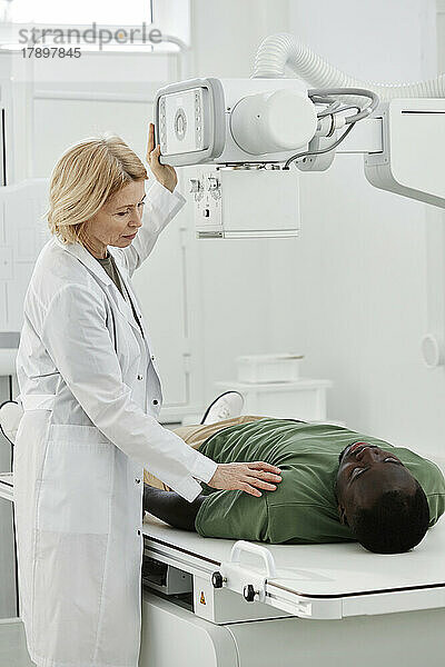 Arzt weist Patienten an  der in der Klinik auf einem Röntgengerät liegt
