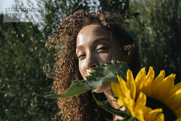 Junge Frau mit Sonnenblume an einem sonnigen Tag
