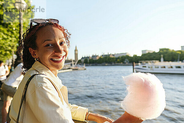Glückliche Frau hält Zuckerwatte an der Themse