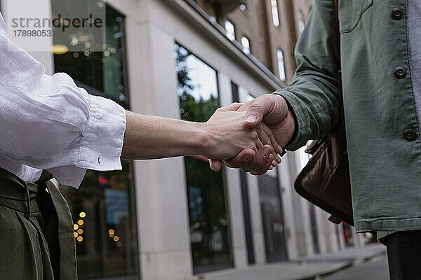 Man and woman doing handshake in front of building