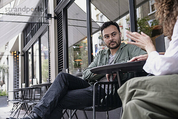 Mann sitzt mit Freundin am Tisch im Straßencafé