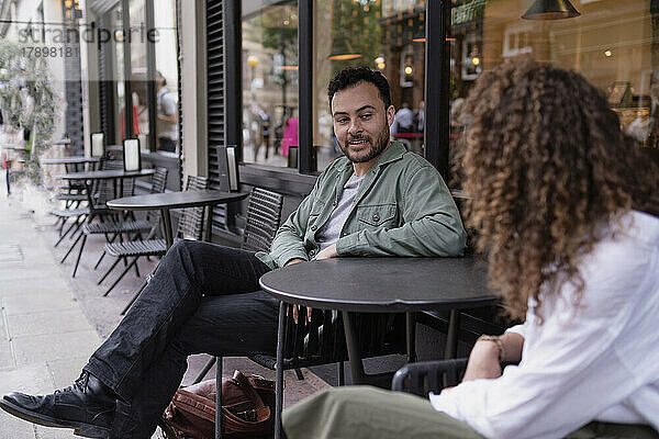 Smiling man with woman sitting at table in sidewalk cafe
