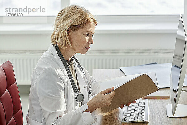 Arzt liest medizinischen Bericht am Schreibtisch in der Klinik