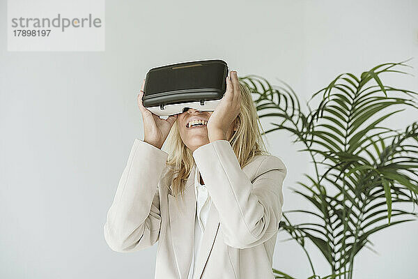 Glückliche Geschäftsfrau mit VR-Brille im Büro