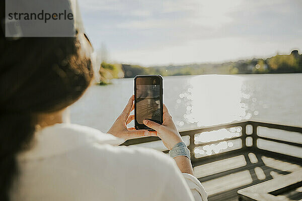 Junge Frau fotografiert an einem sonnigen Tag mit dem Smartphone