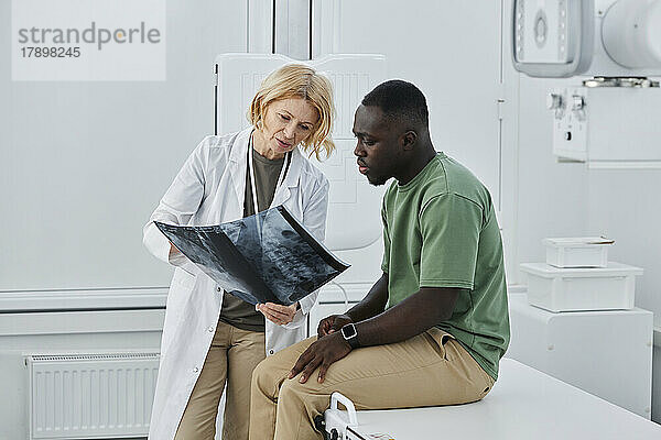 Arzt und Patient diskutieren über Röntgenaufnahmen in der Klinik
